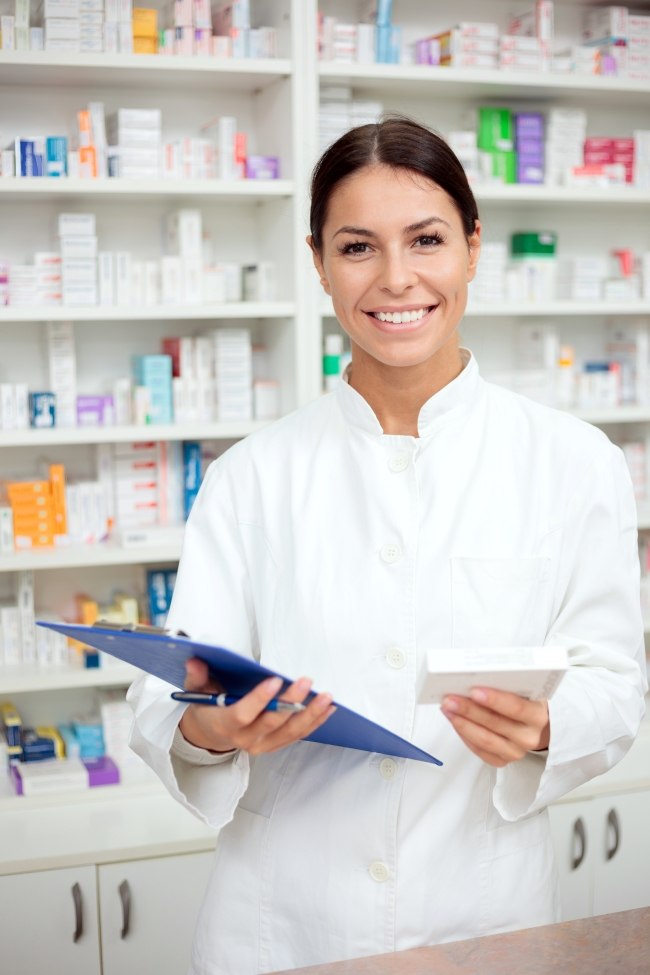 Female pharmacist with clipboard behind the counter